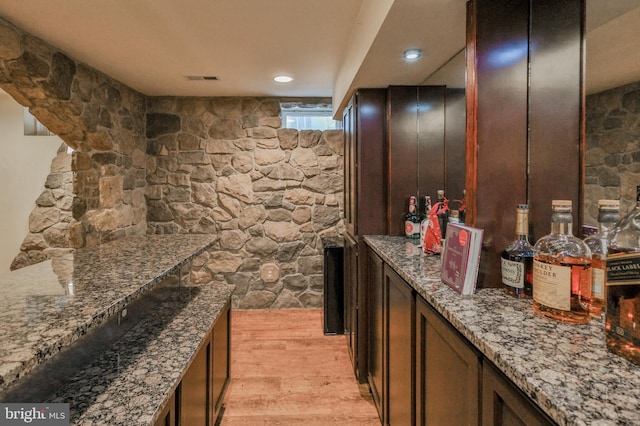 indoor dry bar featuring light wood-style flooring