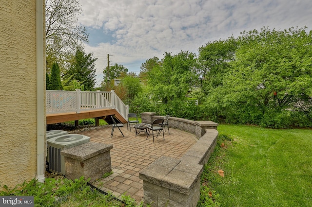 view of patio featuring a fire pit, a wooden deck, central AC, and view of wooded area