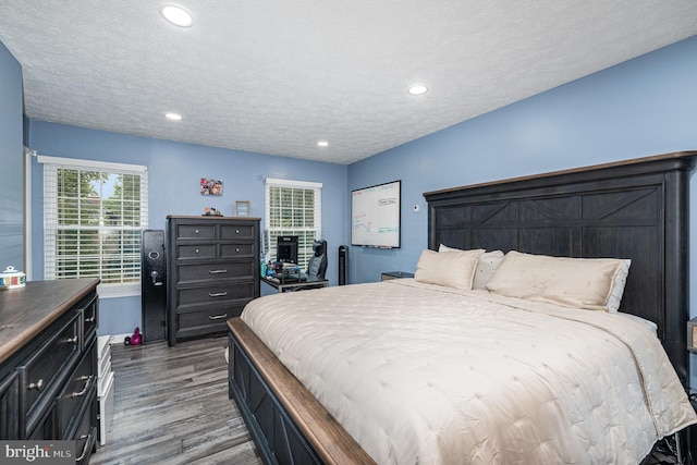 bedroom with wood finished floors, recessed lighting, and a textured ceiling