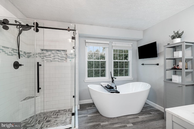 full bathroom with wood finished floors, a stall shower, a soaking tub, baseboards, and a textured ceiling