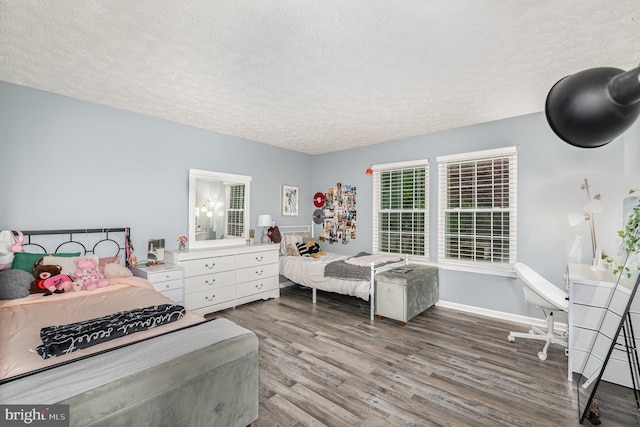 bedroom with a textured ceiling, wood finished floors, and baseboards
