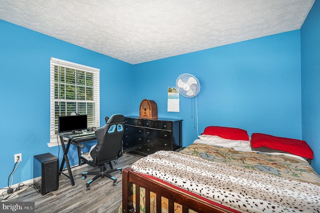 bedroom with wood finished floors, a textured ceiling, a desk, and baseboards