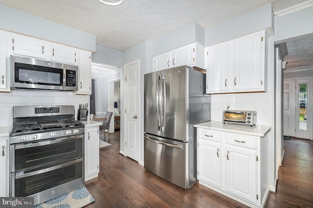 kitchen with appliances with stainless steel finishes, light countertops, white cabinets, a textured ceiling, and ornamental molding