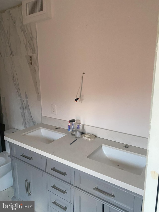 full bath with double vanity, marble finish flooring, and toilet