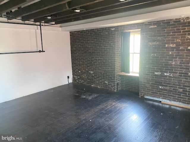 basement with wood finished floors and brick wall