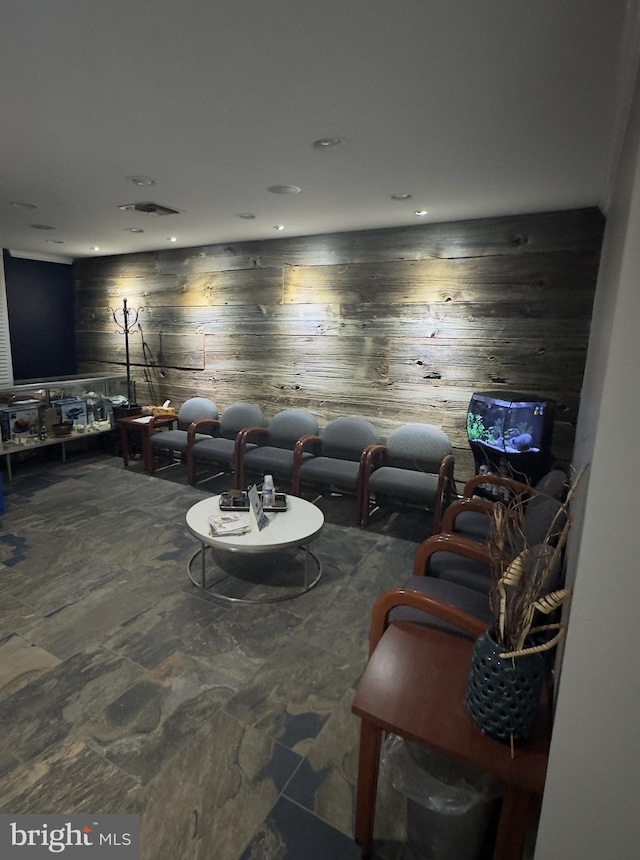 living room with stone floors, wooden walls, and recessed lighting