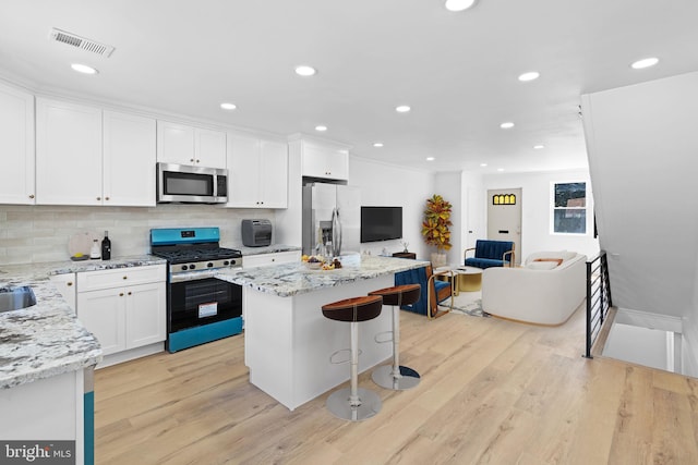 kitchen featuring stainless steel appliances, a center island, light wood-style floors, decorative backsplash, and recessed lighting