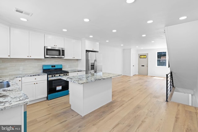 kitchen featuring appliances with stainless steel finishes, a center island, tasteful backsplash, white cabinets, and recessed lighting