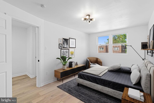 bedroom with light wood-style floors, a chandelier, and baseboards