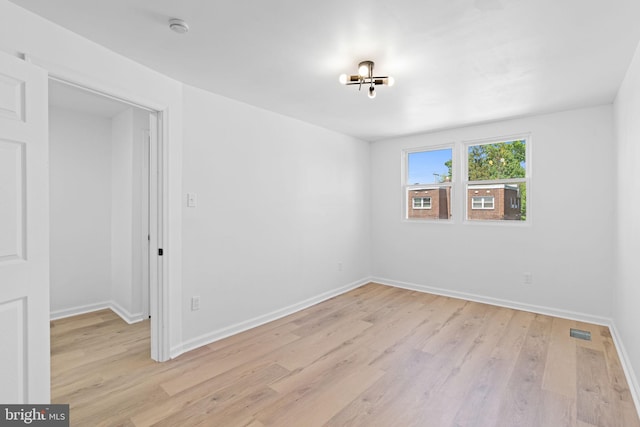 spare room with light wood finished floors, a smoke detector, and baseboards