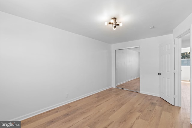 unfurnished bedroom featuring light wood-type flooring, baseboards, and a closet