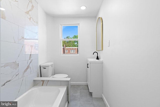 bathroom with a tub to relax in, vanity, tile patterned floors, baseboards, and toilet