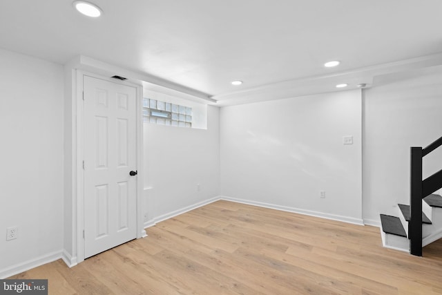 below grade area with recessed lighting, light wood-type flooring, baseboards, and stairs