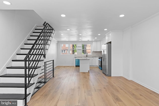 kitchen featuring freestanding refrigerator, white cabinets, recessed lighting, a kitchen island, and light wood-style flooring
