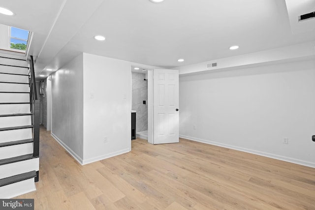 below grade area with baseboards, stairs, recessed lighting, and light wood-type flooring