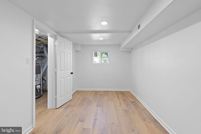 below grade area featuring water heater, light wood-style floors, baseboards, and recessed lighting