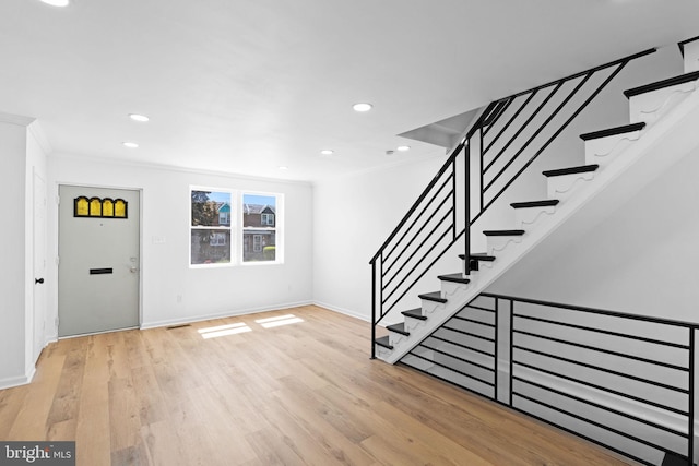 entryway with ornamental molding, baseboards, light wood-style flooring, recessed lighting, and stairs