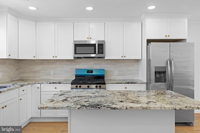 kitchen with appliances with stainless steel finishes, white cabinetry, light stone countertops, light wood finished floors, and recessed lighting