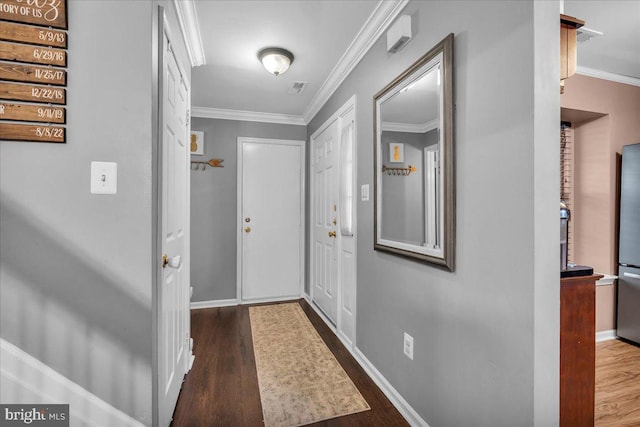 doorway to outside with wood finished floors, ornamental molding, and baseboards