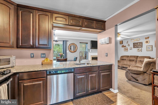 kitchen featuring stainless steel appliances, a sink, ceiling fan, crown molding, and open floor plan
