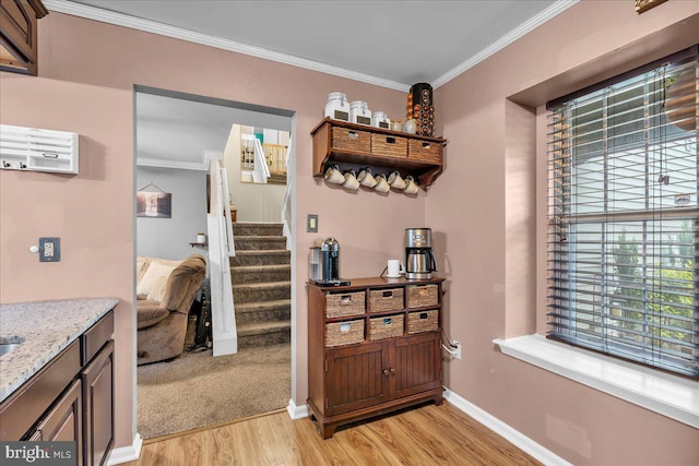 corridor with light wood-style flooring, crown molding, stairs, and baseboards