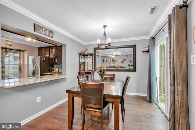 dining space with plenty of natural light, a chandelier, crown molding, and dark wood-style floors