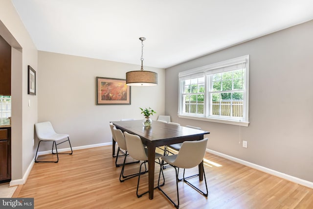 dining space with light wood-type flooring and baseboards
