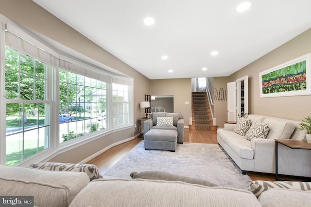 living area with plenty of natural light, stairs, recessed lighting, wood finished floors, and baseboards