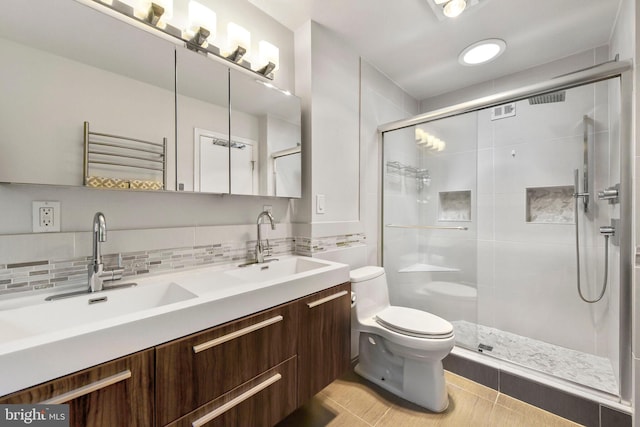 full bathroom with toilet, a stall shower, double vanity, backsplash, and a towel warmer