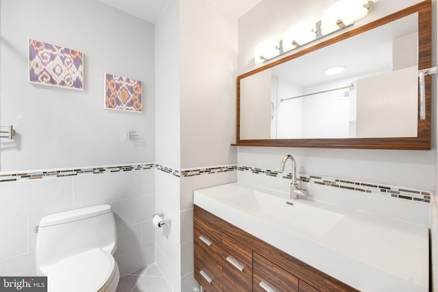 bathroom with tile walls, toilet, vanity, and wainscoting