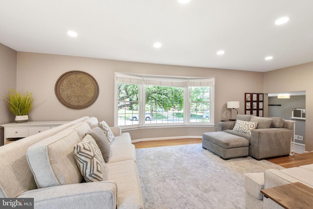 living room with wood finished floors, recessed lighting, and a wall unit AC