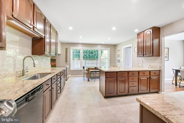 kitchen featuring a sink, dishwasher, baseboards, backsplash, and light stone countertops