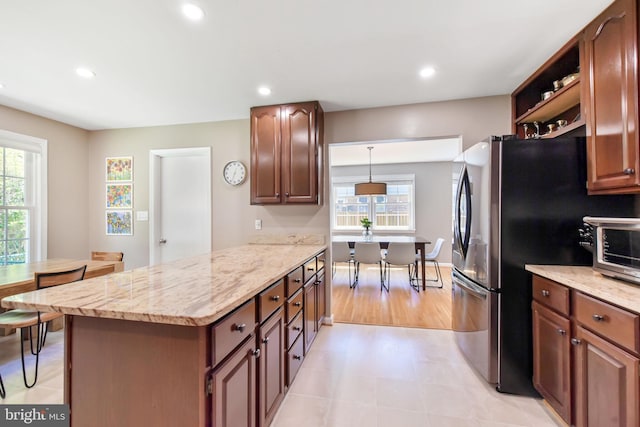 kitchen featuring freestanding refrigerator, light stone counters, recessed lighting, a peninsula, and open shelves