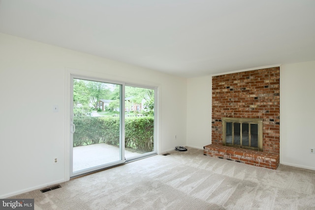 unfurnished living room with carpet flooring, a brick fireplace, and baseboards