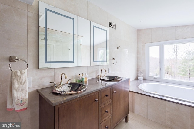bathroom with tile walls, a bath, double vanity, and tile patterned floors