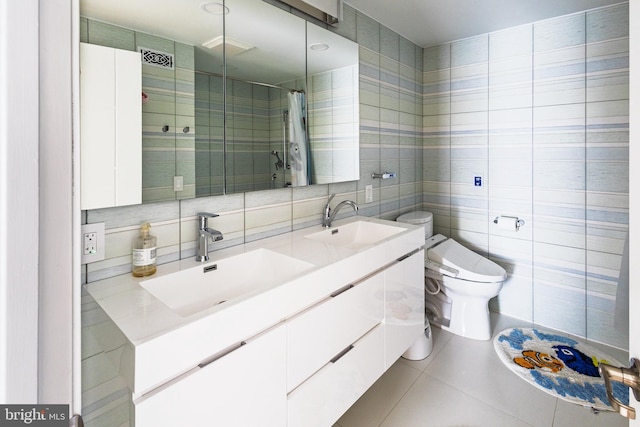 full bathroom featuring tile walls, tiled shower, toilet, tile patterned floors, and double vanity