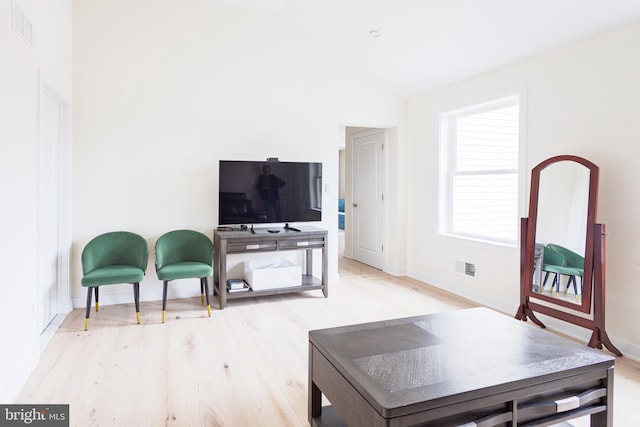 living area featuring wood finished floors, baseboards, and vaulted ceiling
