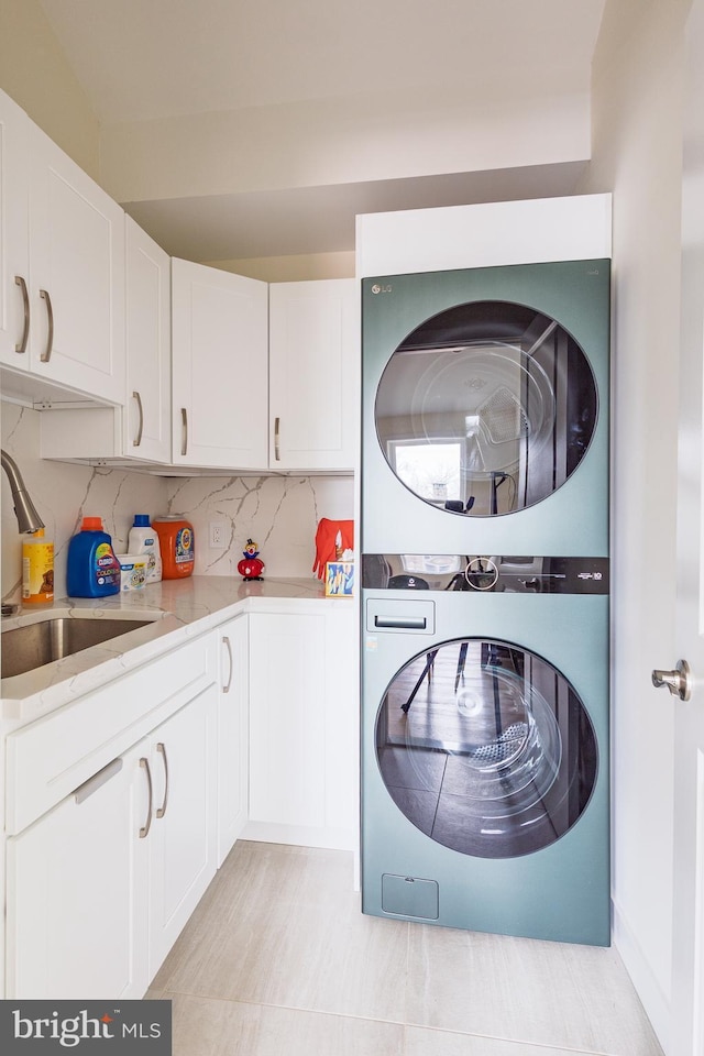 clothes washing area featuring stacked washer / dryer and cabinet space