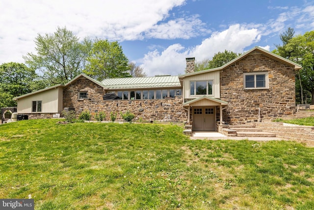 mid-century modern home with stone siding, a chimney, and a front lawn