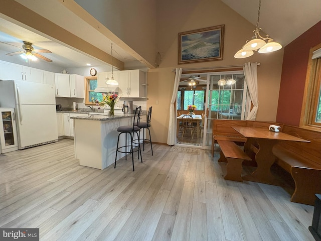 kitchen with ceiling fan, freestanding refrigerator, a peninsula, white cabinetry, and high vaulted ceiling