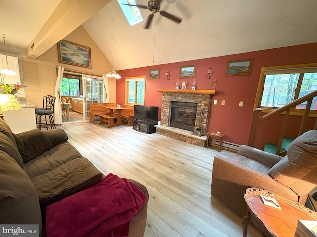 living area featuring ceiling fan, wood finished floors, healthy amount of natural light, a brick fireplace, and high vaulted ceiling