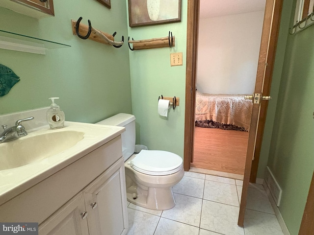 ensuite bathroom with toilet, vanity, and tile patterned floors
