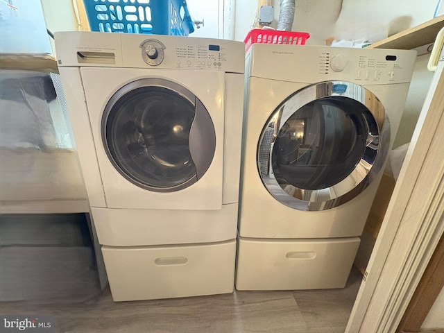 laundry area with washer and dryer and wood finished floors