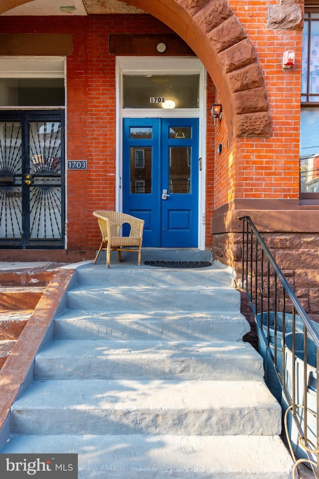view of exterior entry with french doors, brick siding, and covered porch