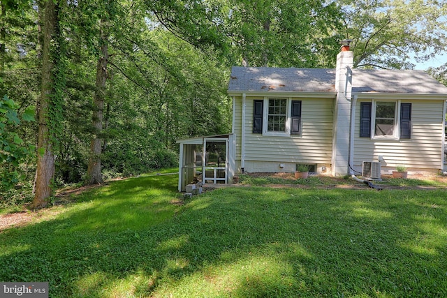 14308 Bristow Rd, Manassas, VA 20112 - back of property featuring central AC unit, a chimney, a lawn, a sunroom, and a shingled roof