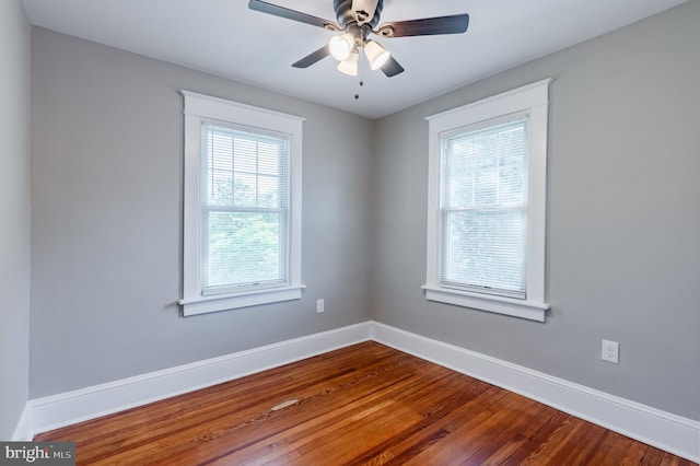 empty room featuring baseboards, dark wood finished floors, and ceiling fan