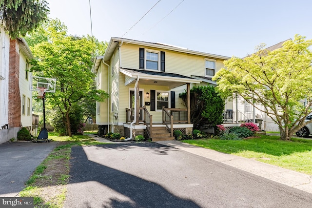 traditional style home featuring covered porch, driveway, and a front lawn