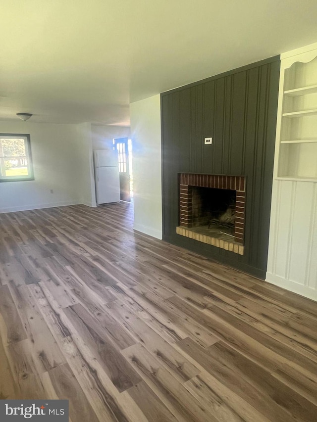 1807 Calvary Church Rd, Warsaw, VA 22572 - unfurnished living room featuring wood finished floors, a brick fireplace, and baseboards