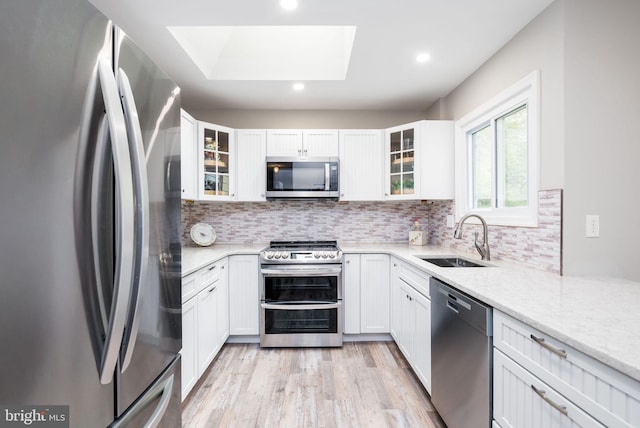 13 Deerfield Ln, Rehoboth Beach, DE 19971 - kitchen with stainless steel appliances, a sink, a skylight, light wood finished floors, and backsplash
