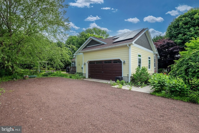 13 Deerfield Ln, Rehoboth Beach, DE 19971 - view of side of property with solar panels, asphalt driveway, cooling unit, a garage, and roof with shingles